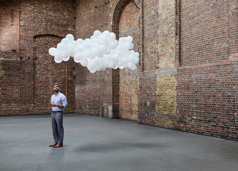 Man In Warehouse With Cloud Of Balloons Above Head Picture Id514351105
