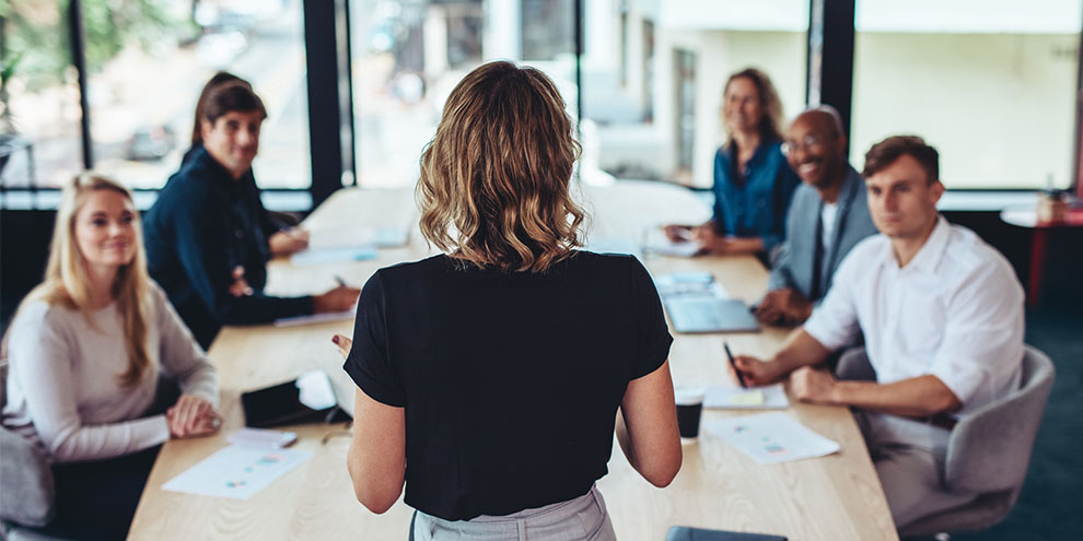 Woman Presenting To Table Of 5 People
